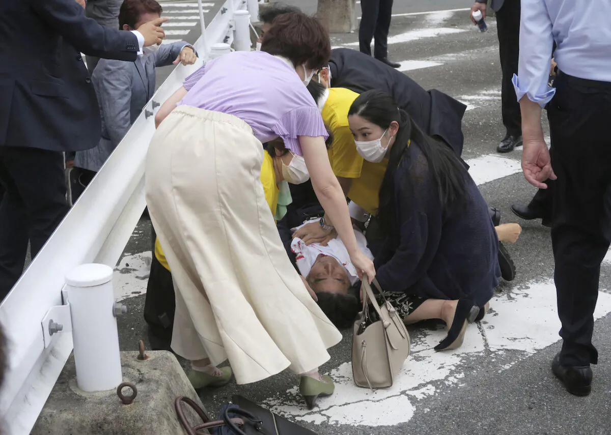 Japan’s former Prime Minister Shinzo Abe, center, falls on the ground in Nara, western Japan Friday, July 8, 2022. (Kyodo News via AP)