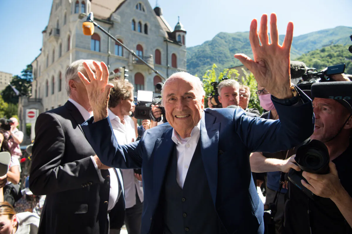 Former FIFA President Joseph Blatter (C), surrounded by media representatives, waves to the press in front of the Swiss Federal Criminal Court, on the last day of the trial, after the verdict has been announced in Bellinzona, Switzerland, on July 8, 2022. (Ti-Press/Alessandro Crinari/Keystone via AP)