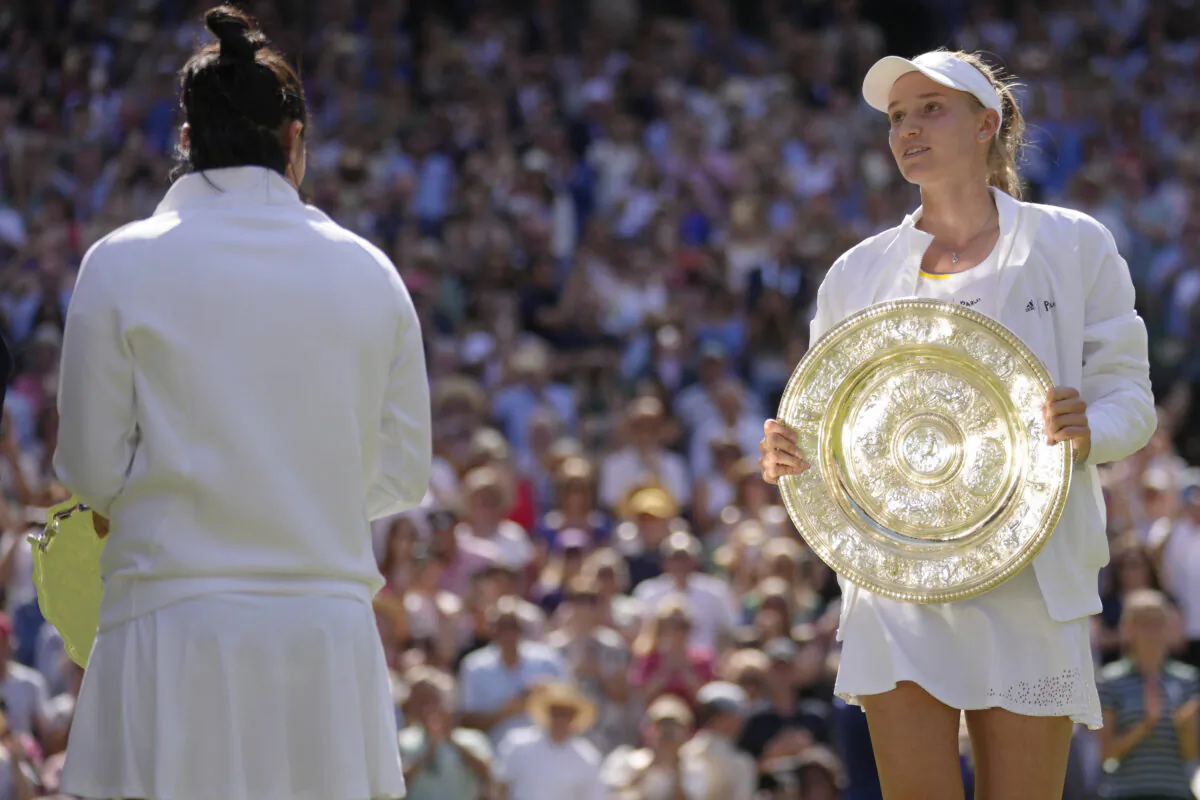 Kazakhstan's Elena Rybakina celebrates with the trophy after beating Tunisia's Ons Jabeur (L), to win the final of the women's singles on day 13 of the Wimbledon tennis championships in London on July 9, 2022. (Kirsty Wigglesworth/AP Photo)