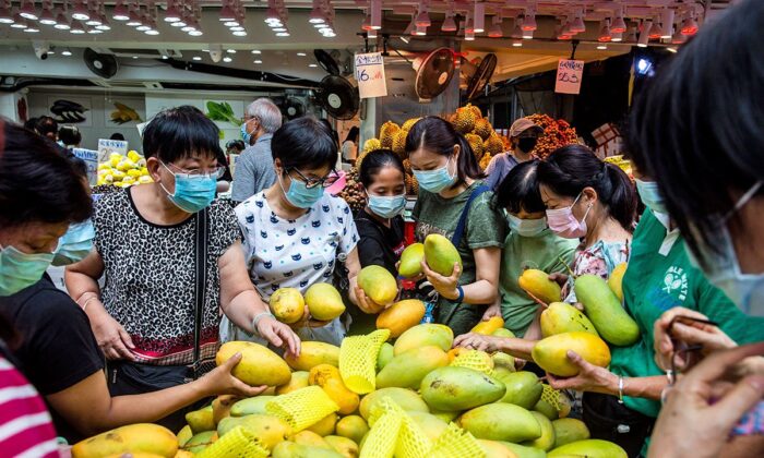 People buying mangoes at a fruit stall in Hong Kong. The Hong Kong government said on July 6, 2022, that the mangoes imported from Taiwan tested positive for COVID-19, and has ordered vendors to stop selling them and to destroy them all.  (Isaac Lawrence/AFP)
