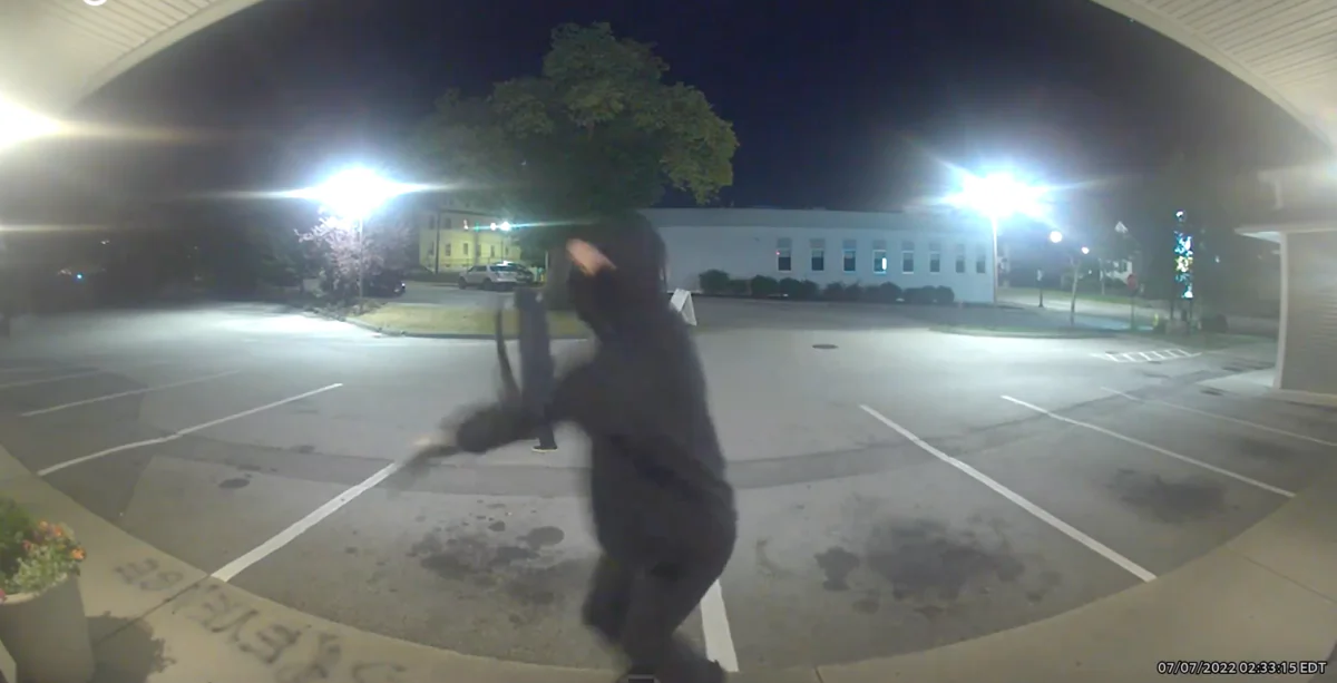 A masked assailant winds up to swing a hammer at a pregnancy clinic in Worcester, Mass., on July 7, 2022. (Still from surveillance video/The Problem Pregnancy)