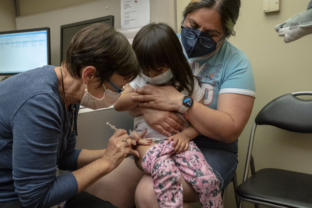 A 2-year-old receives her first dose of the Pfizer COVID-19 vaccination from a nurse while being held by her mother, at UW Medical Center – Roosevelt in Seattle on June 21, 2022. (David Ryder/Getty Images)