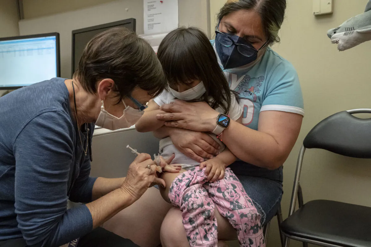 A 2-year-old receives her first dose of the Pfizer COVID-19 vaccination from a nurse while being held by her mother, at UW Medical Center - Roosevelt in Seattle, Wash., on June 21, 2022. (David Ryder/Getty Images)