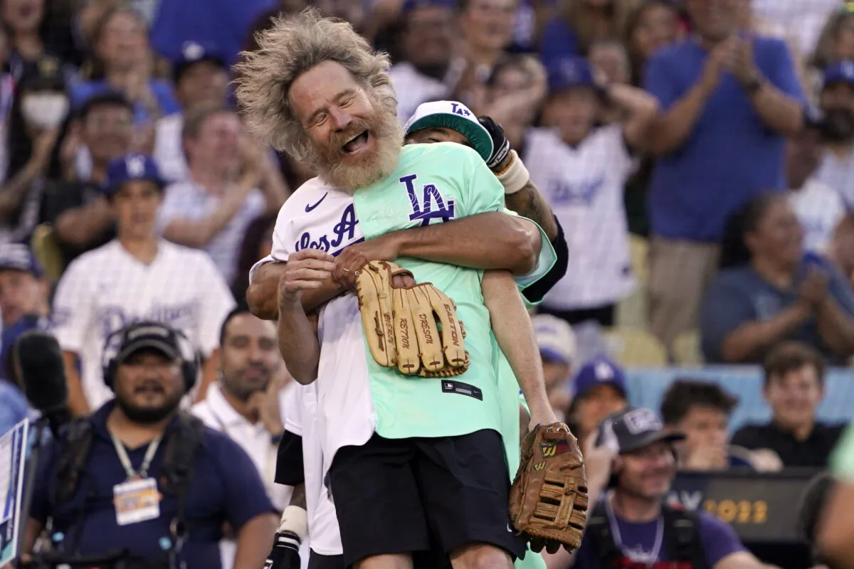 Actor Bryan Cranston is lifted by former Los Angeles Dodgers player Andre Ethier during the MLB All Star Celebrity Softball game in Los Angeles on July 16, 2022. (Mark J. Terrill/AP Photo)