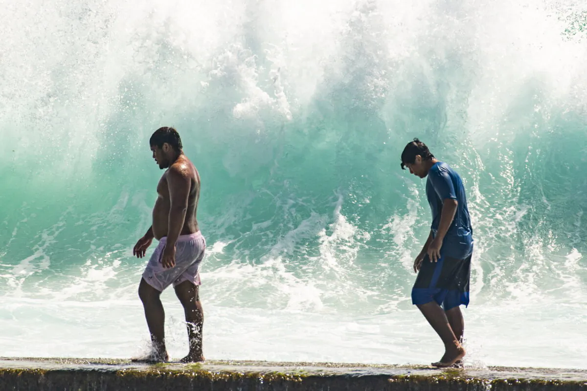 People walk in front of the high surf near Kapahulu Groin (Waikiki Wall) in Waikiki, Hawaii, on July 17, 2022. (Craig T. Kojima/Honolulu Star-Advertiser via AP)