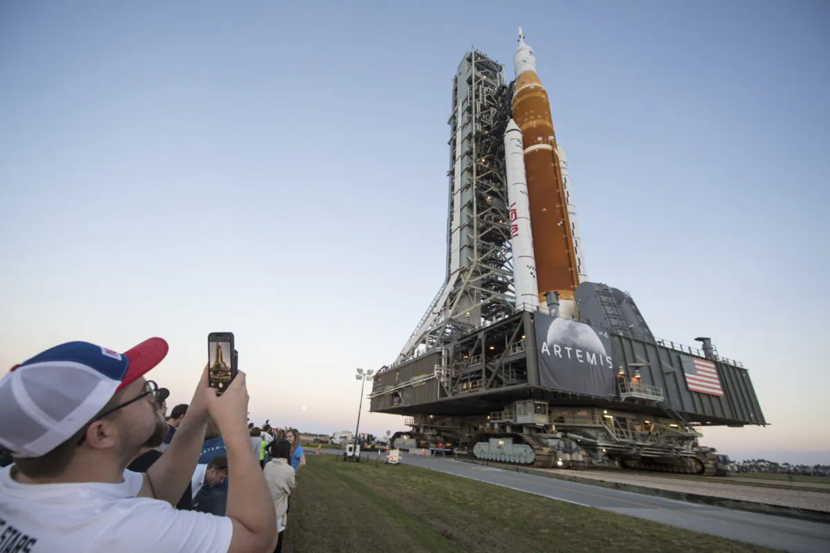 Invited guests and NASA employees take photos as NASA's Space Launch System (SLS) rocket with the Orion spacecraft aboard is rolled out of High Bay 3 of the Vehicle Assembly Building for the first time, at the Kennedy Space Center in Cape Canaveral, Fla., on March 17, 2022. (Aubrey Gemignani/NASA via AP)
