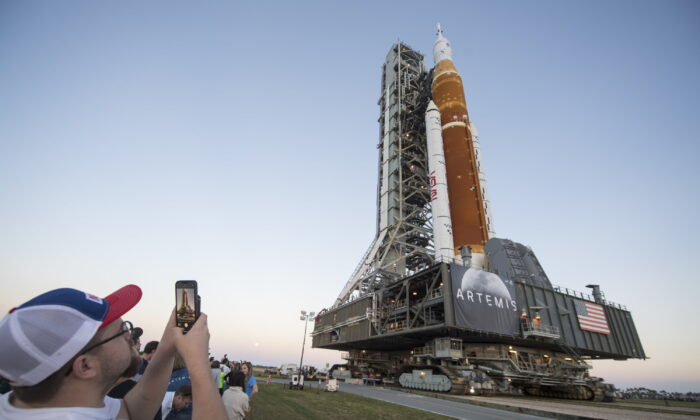 Invited guests and NASA employees take photos as NASA's Space Launch System (SLS) rocket with the Orion spacecraft aboard is rolled out of High Bay 3 of the Vehicle Assembly Building for the first time, at the Kennedy Space Center in Cape Canaveral, Fla., on March 17, 2022. (Aubrey Gemignani/NASA via AP)