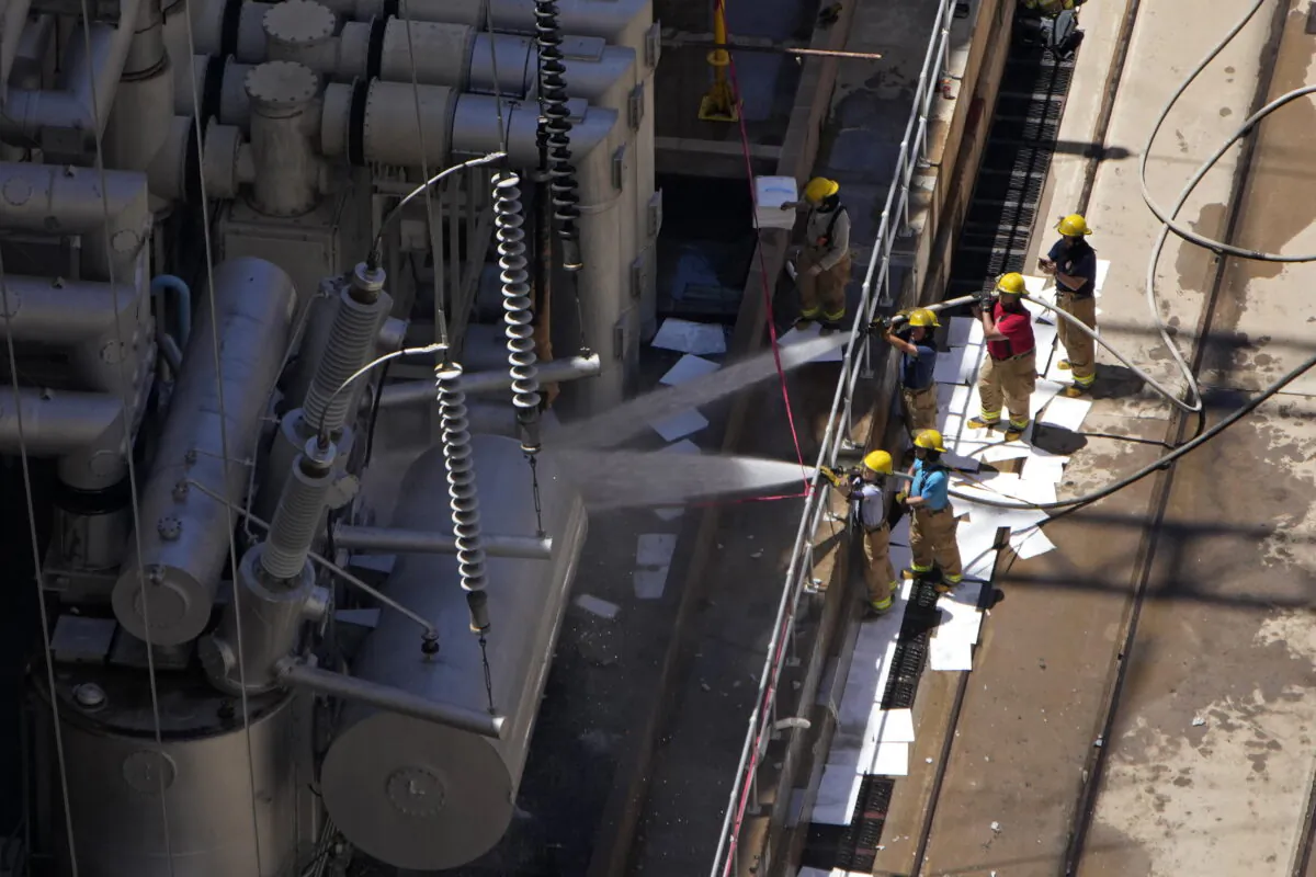 Firefighters spray water after a fire on the Arizona side of the Hoover Dam, near Boulder City, Nev., on July 19, 2022. (John Locher/AP Photo)