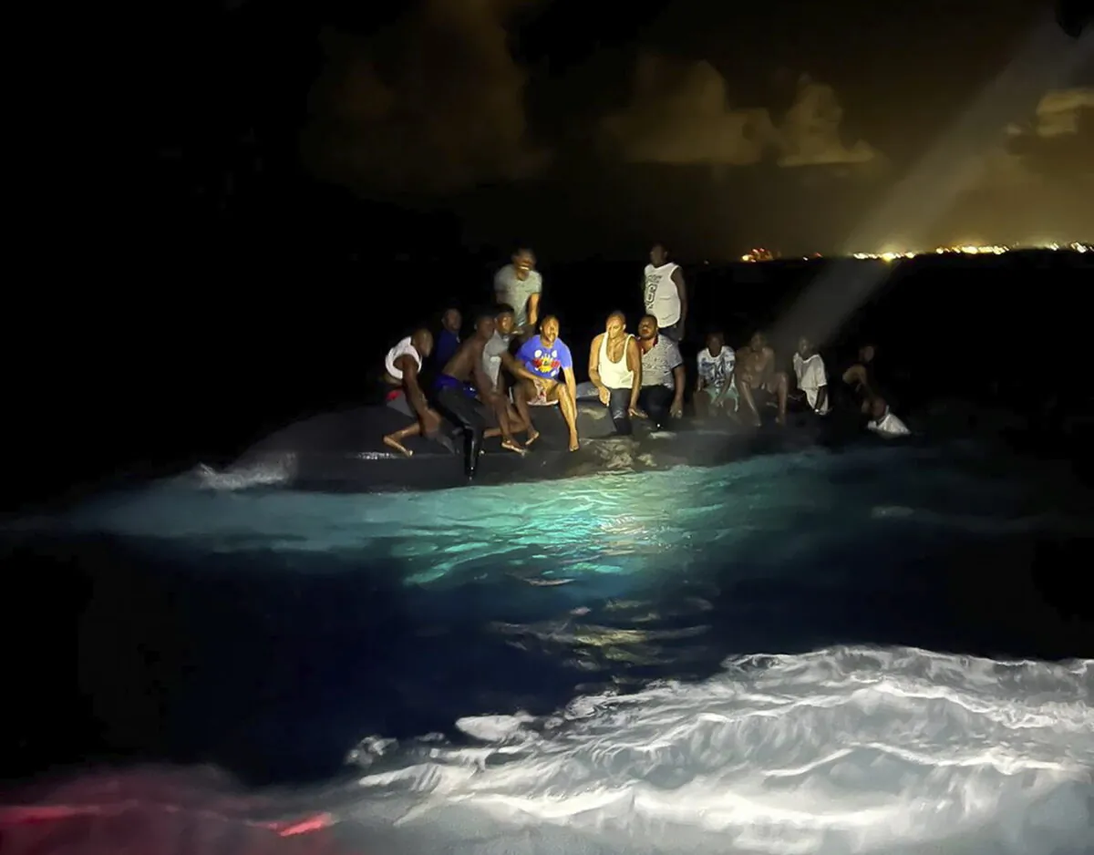Survivors sit on a capsized boat as they are about to be rescued near New Providence in the Bahamas, early on July 24, 2022. (Royal Bahamas Defense Force via AP)