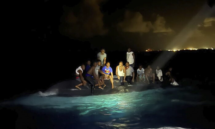 Survivors sit on a capsized boat as they are about to be rescued near New Providence in the Bahamas, early on July 24, 2022. (Royal Bahamas Defense Force via AP)