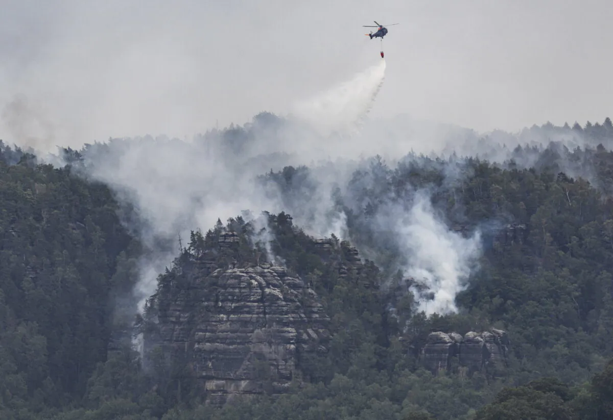 A helicopter of the German Federal Police battles wildfires in the Saxon Switzerland National Park near Schmilka, Germany, Wednesday, July, 27, 2022. (Robert Michael/dpa via AP)