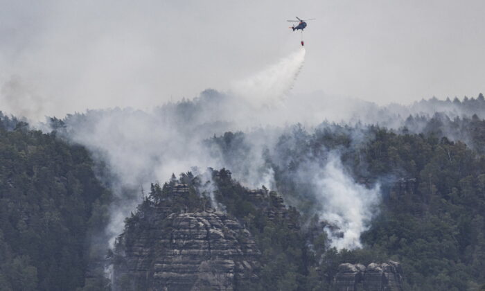 A helicopter of the German Federal Police battles wildfires in the Saxon Switzerland National Park near Schmilka, Germany, Wednesday, July, 27, 2022. (Robert Michael/dpa via AP)