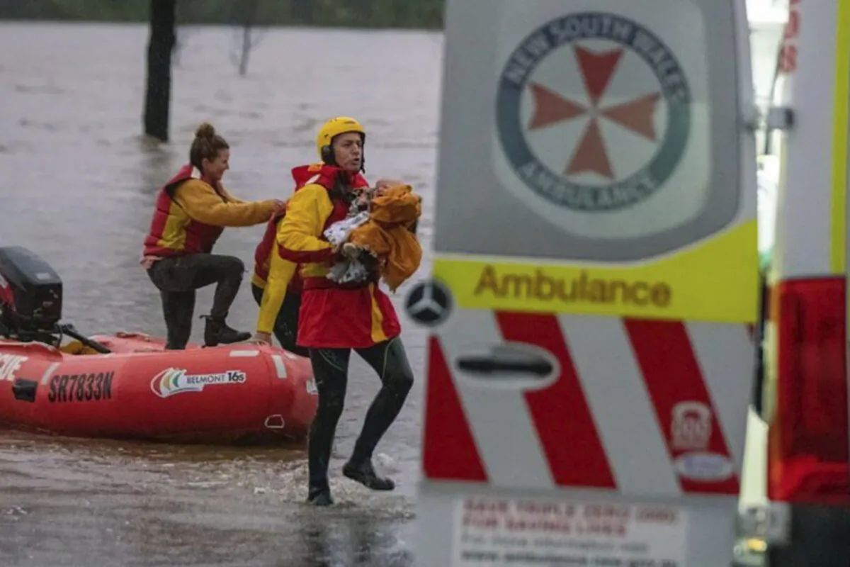 In this photo provided by the State Emergency Service, surf lifesaver Lee Archer carries a baby as the child and the mother are rescued from flood waters in Bulga, Australia, Wednesday, July, 6, 2022. (State Emergency Service via AP)