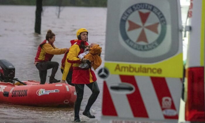 In this photo provided by the State Emergency Service, surf lifesaver Lee Archer carries a baby as the child and the mother are rescued from flood waters in Bulga, Australia, Wednesday, July, 6, 2022. (State Emergency Service via AP)