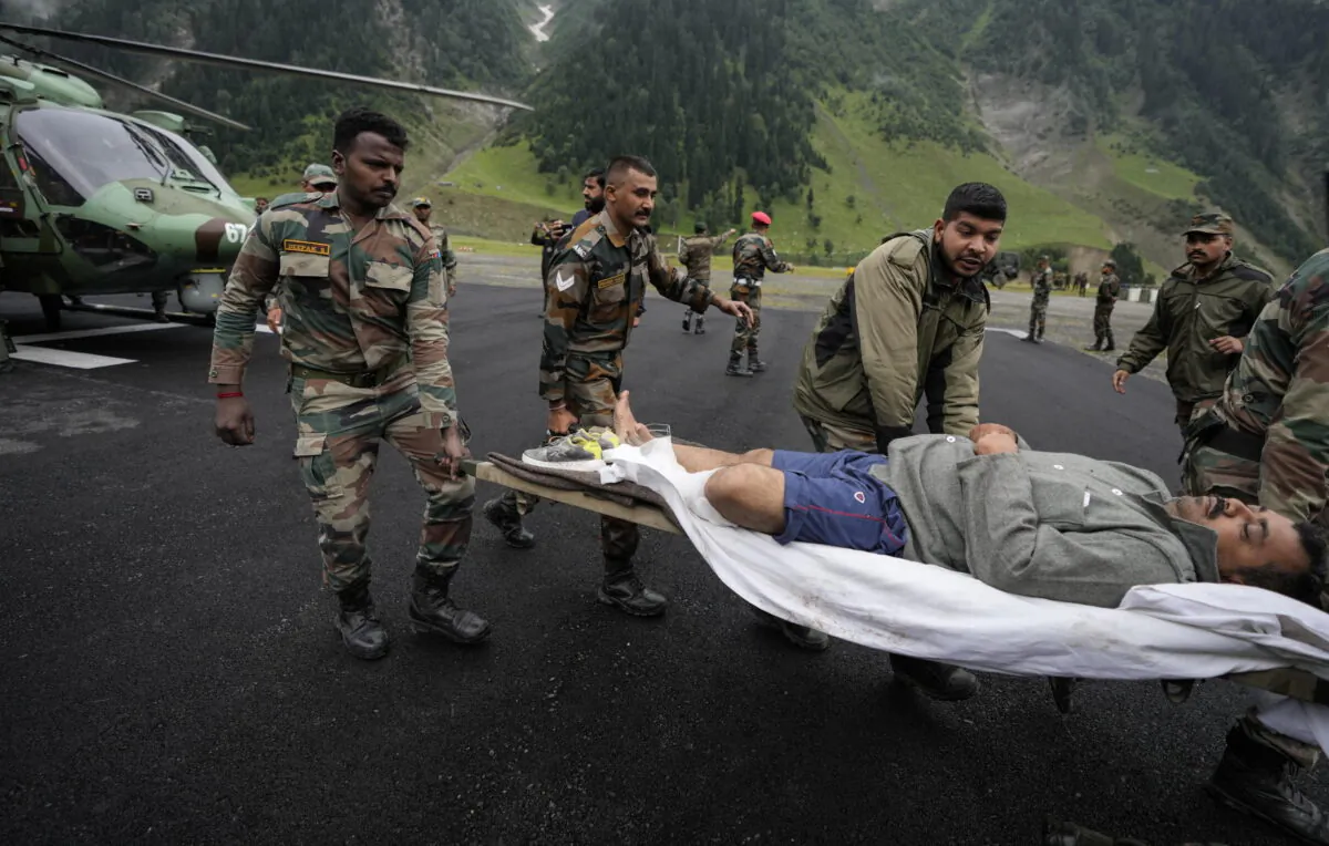 Indian army soldiers carry an injured of a cloudburst for treatment, at Baltal, 105 kilometers (65miles) northeast of Srinagar, Indian controlled Kashmir, on July 9, 2022. (Mukhtar Khan/AP Photo)
