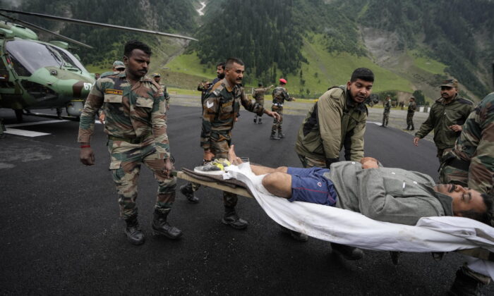 Indian army soldiers carry an injured of a cloudburst for treatment, at Baltal, 105 kilometers (65miles) northeast of Srinagar, Indian controlled Kashmir, on July 9, 2022. (Mukhtar Khan/AP Photo)