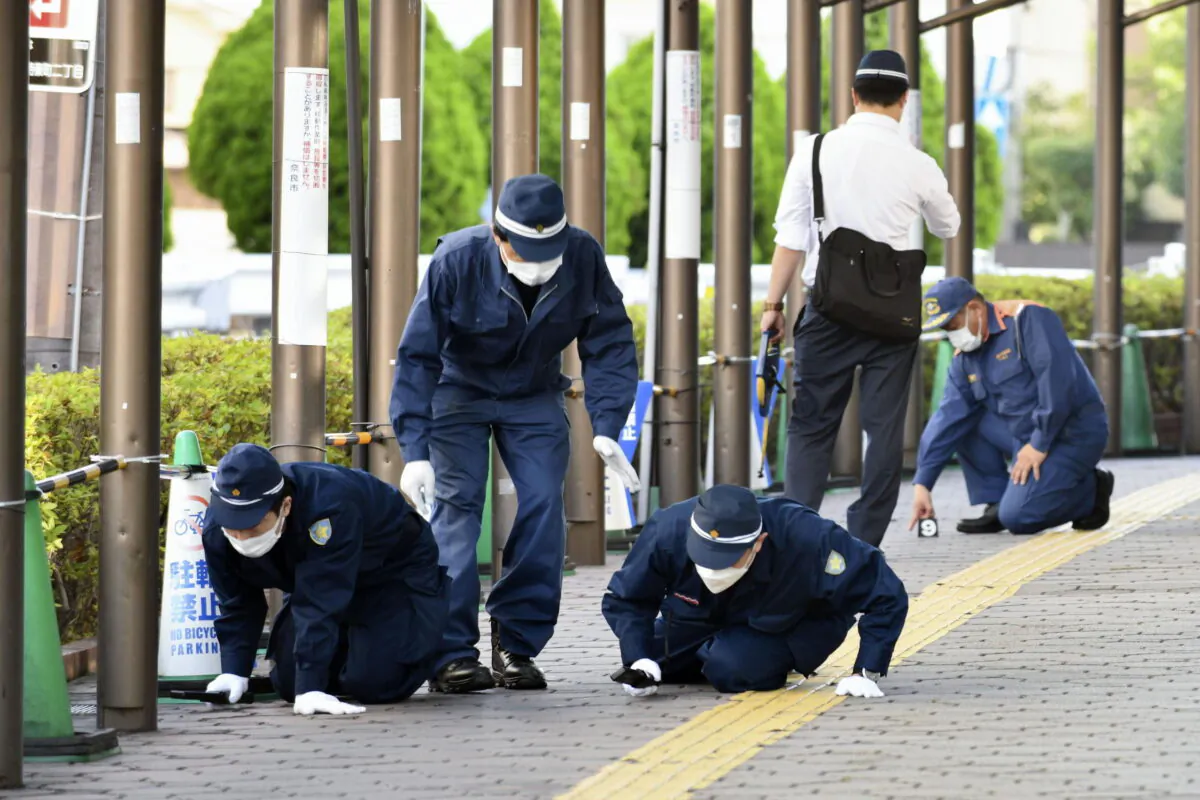 Police inspect a sidewalk near the site where former Japanese Prime Minister Shinzo Abe was fatally shot, in Nara, western Japan, on July 13, 2022. (Kyodo News via AP)