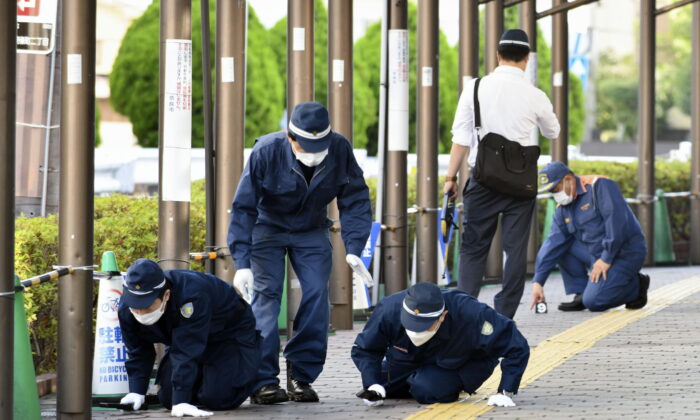 Police inspect a sidewalk near the site where former Japanese Prime Minister Shinzo Abe was fatally shot, in Nara, western Japan, on July 13, 2022. (Kyodo News via AP)
