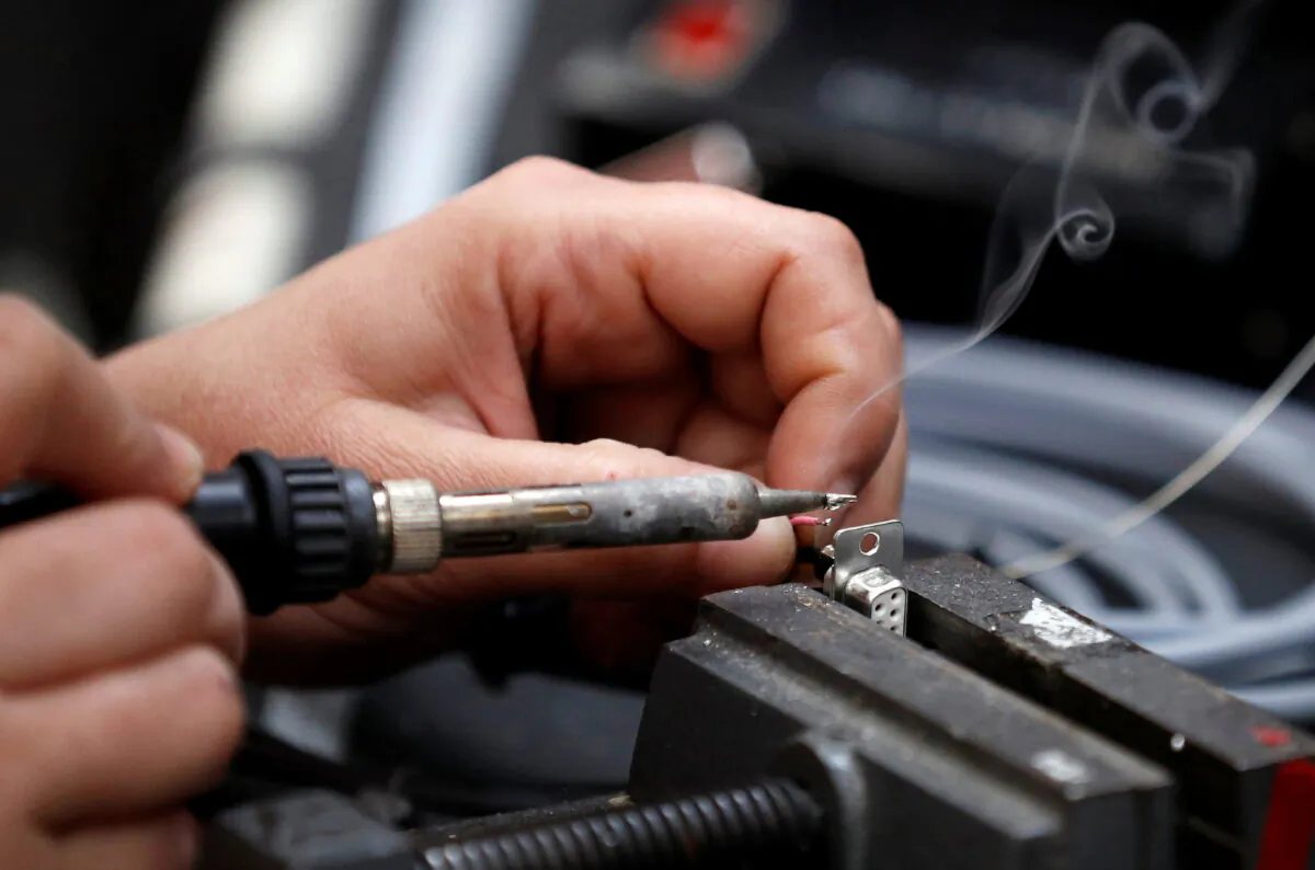 A worker solders electrical wire to a component on the factory floor of PP Control and Automation near Cannock, Britain, on July 6, 2016. (Phil Noble/Reuters)