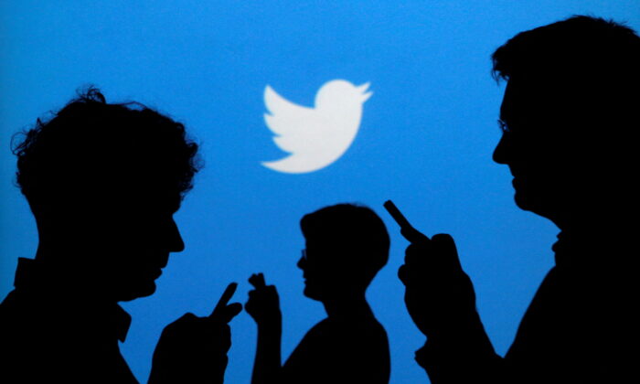 People holding mobile phones are silhouetted against a backdrop projected with the Twitter logo in this illustration picture taken in Warsaw, Poland, on Sept. 27, 2013. (Kacper Pempel/Reuters)