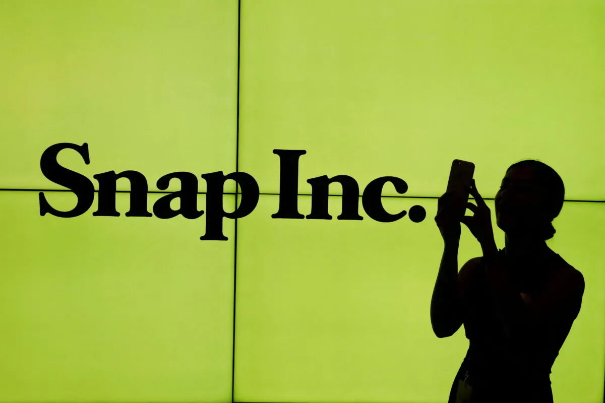 A woman stands in front of the logo of Snap Inc. on the floor of the New York Stock Exchange while waiting for Snap Inc. to post their IPO, in New York on March 2, 2017. (Lucas Jackson/Reuters)