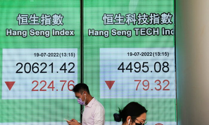 People walk past a screen displaying the Hang Seng stock index at Central district, in Hong Kong on July 19, 2022. (Lam Yik/Reuters)