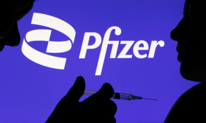 People pose with syringe with needle in front of displayed Pfizer logo in this illustration taken on Dec. 11, 2021. (REUTERS/Dado Ruvic/Illustration/File Photo)