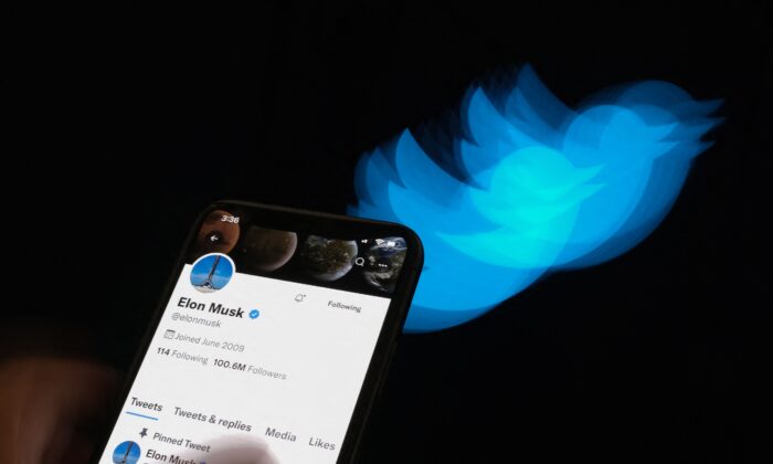 Elon Musk's Twitter page displayed on the screen of a smartphone with Twitter logo in the background in Los Angeles on July 8, 2022. (Chris Delmas/AFP via Getty Images)