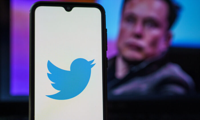The Twitter logo is seen on a smartphone with Elon Musk in the background. (Rokas Tenys/Shuttertock)