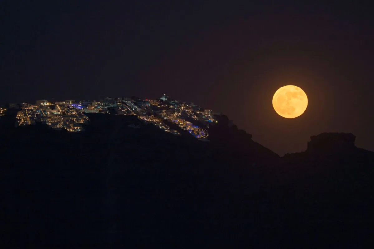 The strawberry supermoon rises behind the village of Imerovigli on Sandorini's caldera, in Greece's Cyclades islands, on June 14, 2022. (Petros Giannakouris/AP Photo)
