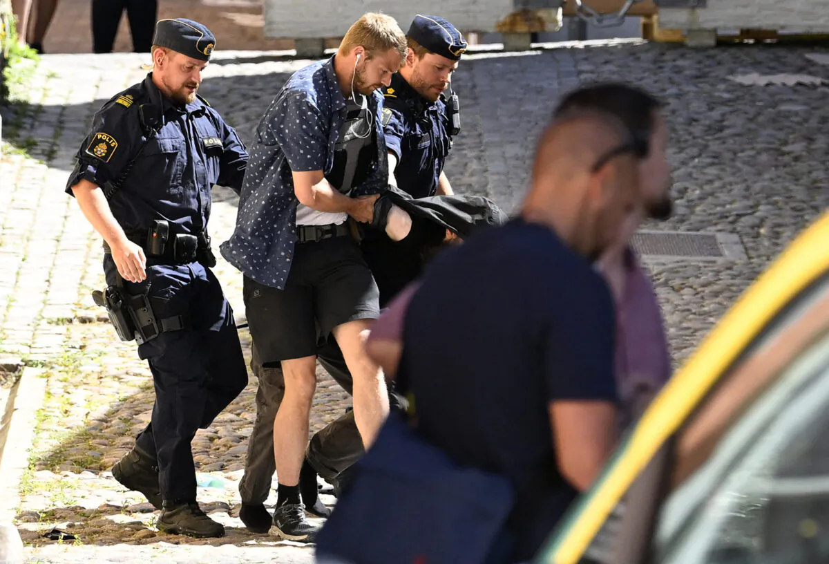Police arrest a man (C hidden) suspected of seriously injuring by stabbing a woman at the Almedalen political festival in Visby on the Swedish island of Gotland on July 6, 2022. (Henrik Montgomery/TT News Agency/AFP via Getty Images)