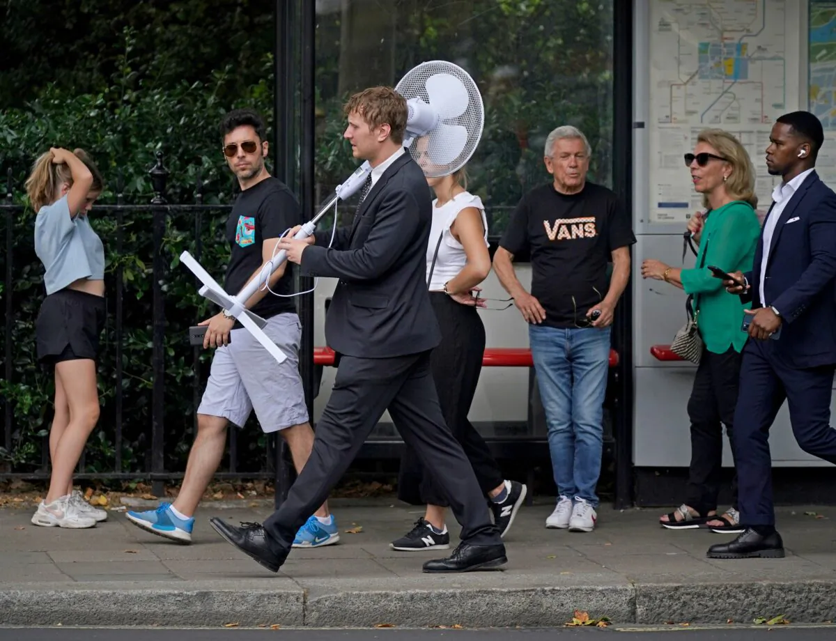 Undated file photo showing an office worker carrying a fan through central London. (Yui Mok/PA Media) 