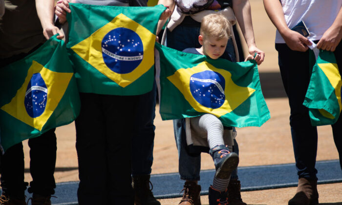 Repatriates from Ukraine hold the Brazilian flag after arriving on the KC-390 Millennium of the Brazilian Air Force in Brasília, Brazil, on March 10, 2022. (Andressa Anholete/Getty Images)