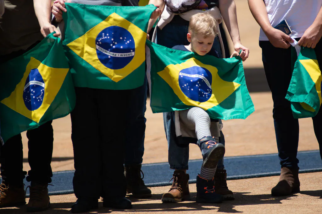 Repatriates from Ukraine hold the Brazilian flag after arriving on the KC-390 Millennium of the Brazilian Air Force in Brasília, Brazil, on March 10, 2022. (Andressa Anholete/Getty Images)
