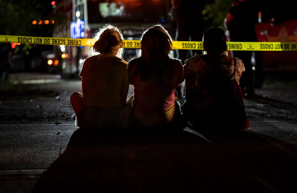 Family and friends watch as Indianapolis Metropolitan Police Department investigators search for a father and three children on Bluff Road in Ind., on July 12, 2022. (Grace Hollars/The Indianapolis Star via AP)