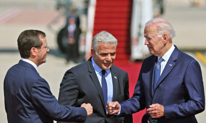 U.S. President Joe Biden (R) bumps fists with Israel's President Isaac Herzog as caretaker Prime Minister Yair Lapid looks on, at Israel's Ben Gurion Airport in Lod near Tel Aviv, on July 13, 2022. (Jack Guez/AFP via Getty Images)