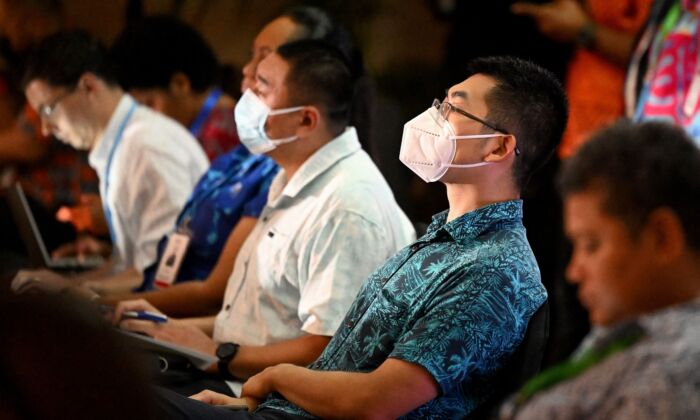 Two officials from the Chinese Embassy (2/R) and (C) listen to US Vice-President Kamala Harris speak via video-link to the Pacific Islands Forum (PIF) in Suva, Fiji, on July 13, 2022. (WILLIAM WEST/AFP via Getty Images)