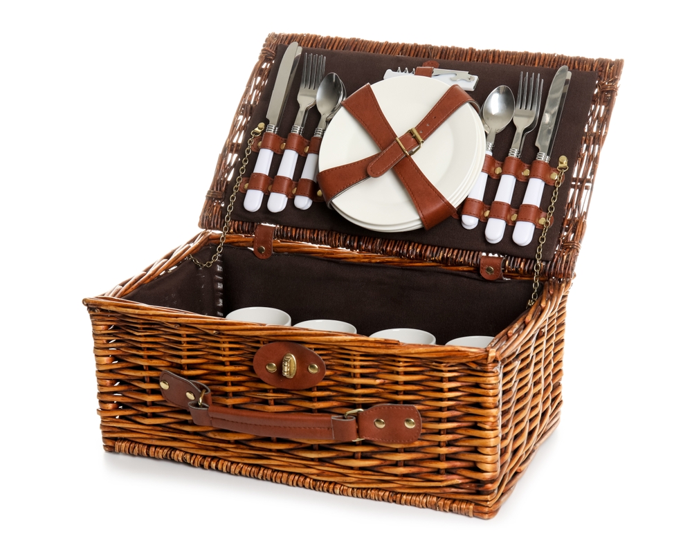 Wicker basket with picnic tableware on a white background