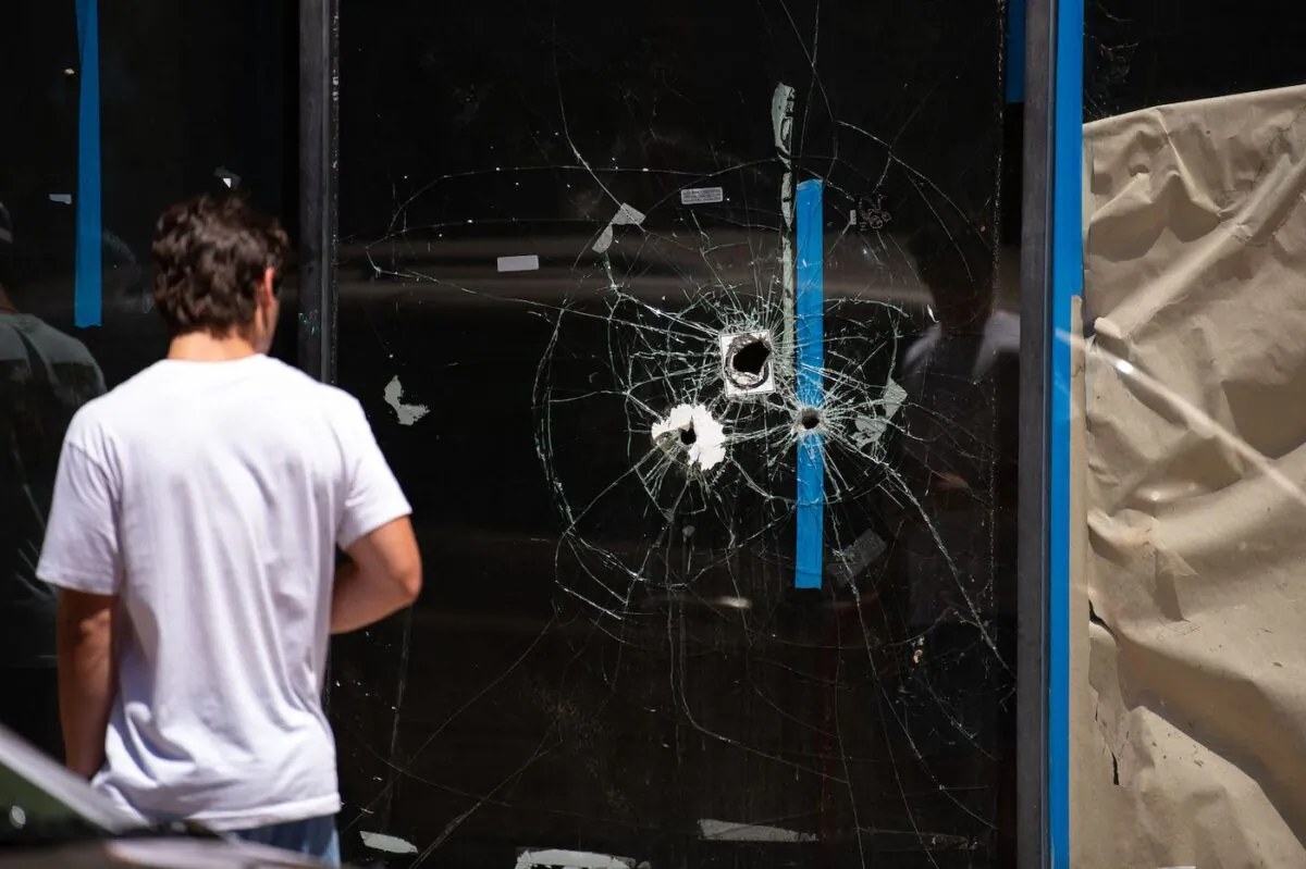 A pedestrian walks past bullet holes in the window of a store front on South Street in Philadelphia, Pa., on June 5, 2022. (Kriston Jae Bethel/AFP/Getty Images)
