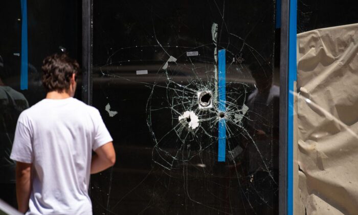 A pedestrian walks past bullet holes in the window of a store front on South Street in Philadelphia, Penn., on June 5, 2022. (Kriston Jae Bethel/AFP/Getty Images)