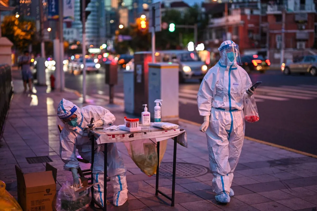 Health workers wait to test people for the Covid-19 on a street next to a residential area in the Jing'an district of Shanghai on July 5, 2022. (Hector Retamal/AFP via Getty Images)