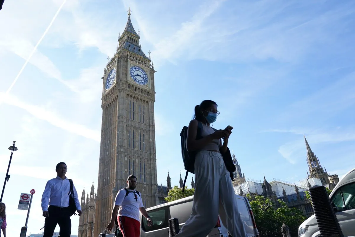 People walk past Big Ben at the Houses of Parliament in London, on July 15, 2022. (Dominic Lipinski/PA Media)