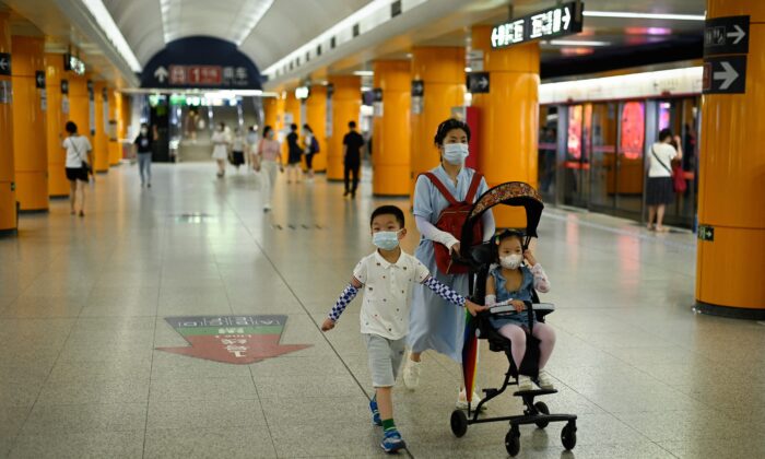 A woman walks in a subway station with two children in Beijing on July 5, 2022. (WANG ZHAO/AFP via Getty Images)