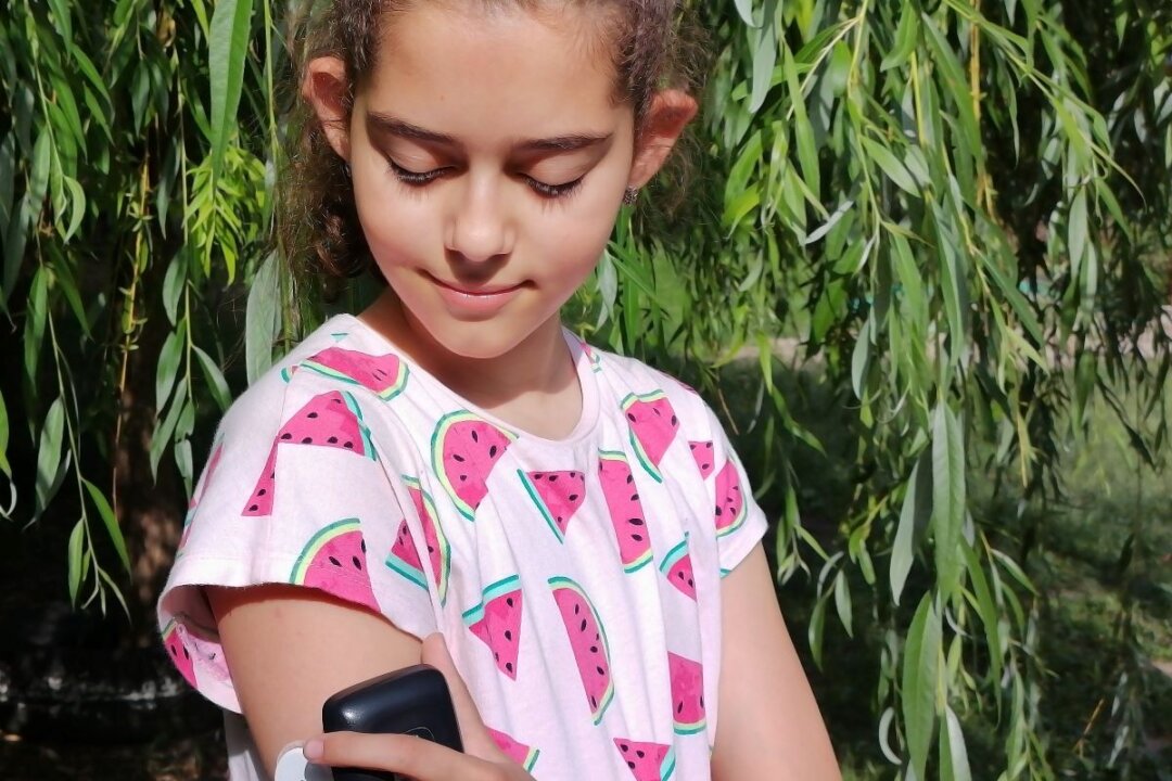 Girl with Type 1 diabetes checks blood glucose level with continuous glucose monitoring device–CGM.
(Dragoljub/Adobe Stock)