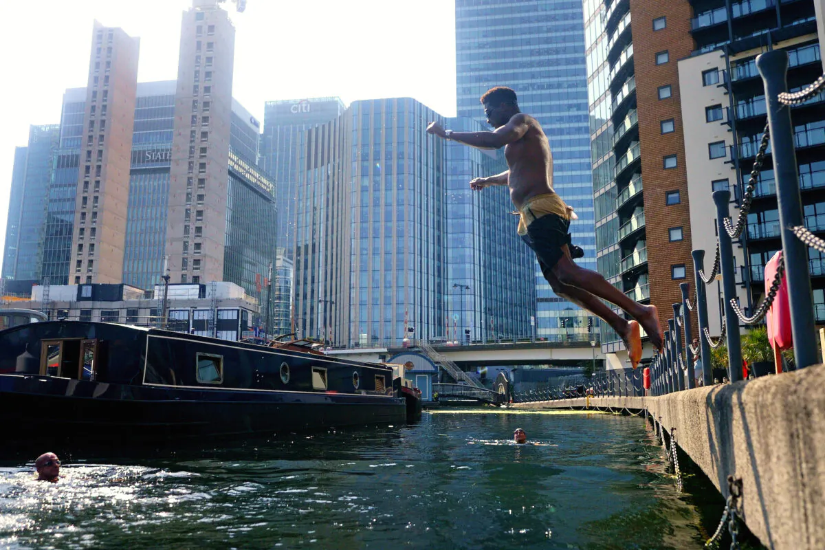 A swimmer dives into water in the Canary Wharf docklands in east London on July 19, 2022. (Victoria Jones/PA Media)