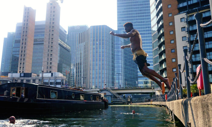 A swimmer dives into water in the Canary Wharf docklands in east London on July 19, 2022. (Victoria Jones/PA Media)