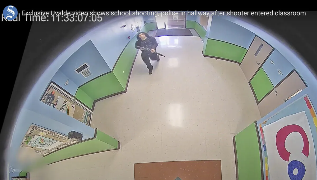 In this image from surveillance video, a gunman carrying a rifle enters and walks down a hallway at Robb Elementary School in Uvalde, Texas, on May 24, 2022. (Uvalde Consolidated Independent School District/Austin American-Statesman via AP)