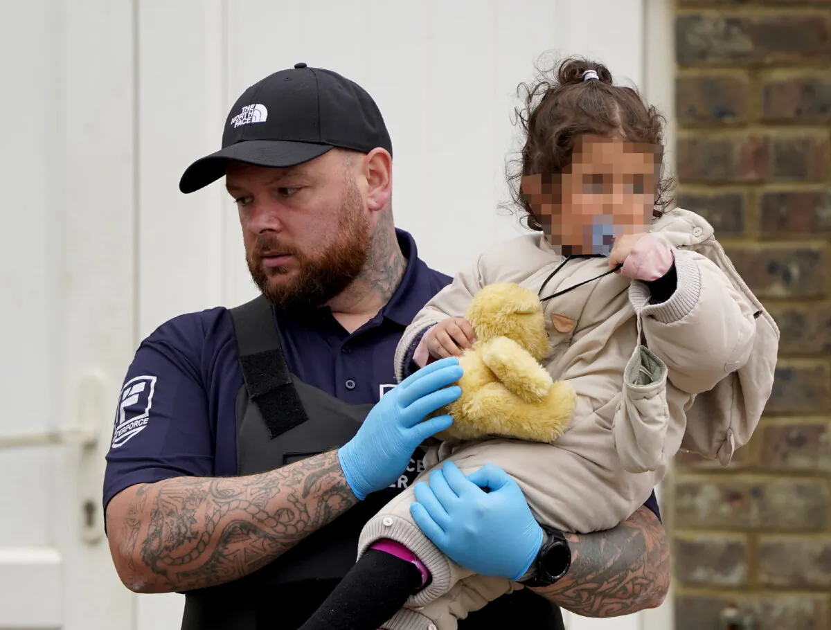 A young girl is carried by a security officer as a group of migrants lands in Dover, Kent, June 7, 2022. (Gareth Fuller/PA)