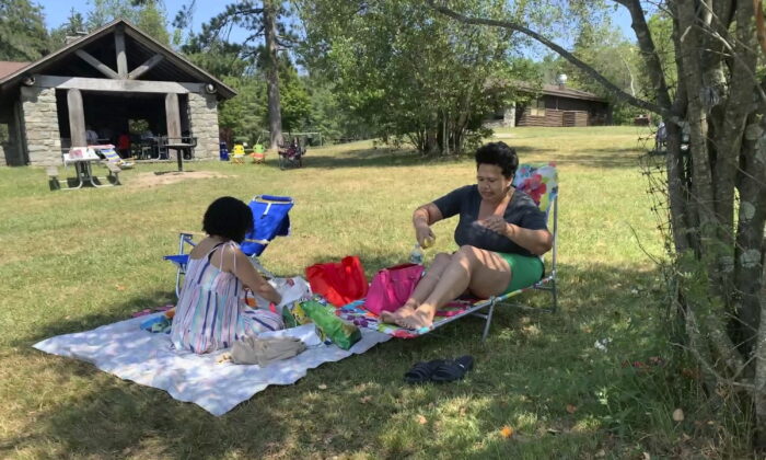 Rosa Chavez of New York applies sunscreen as she and friend Arlene Rodriguez visit Promised Land State Park in Pennsylvania's Pocono Mountains on July 24, 2022. (Jeff McMillan/AP Photo)