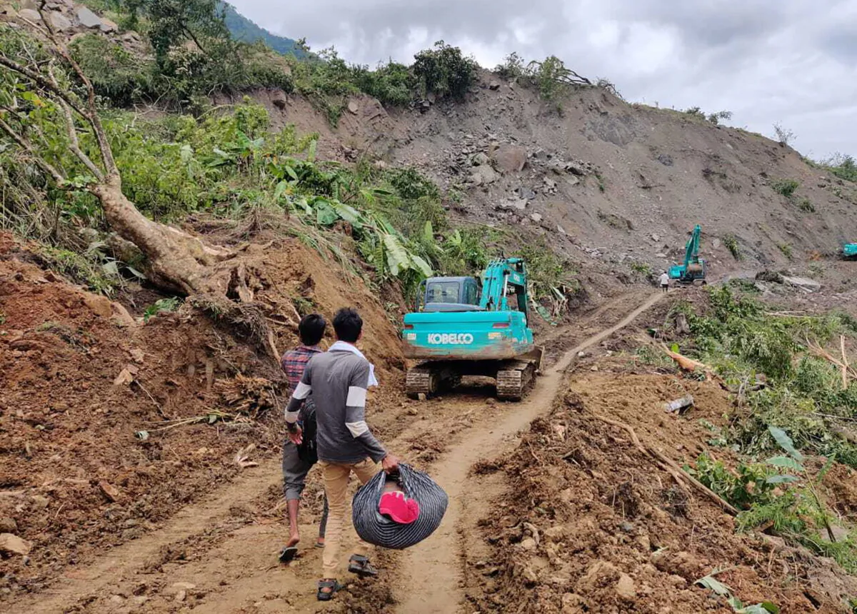 People walk past the site of a mudslide in Noney, northeastern Manipur state, India, on July 1, 2022. (Agui Kamei/AP Photo)